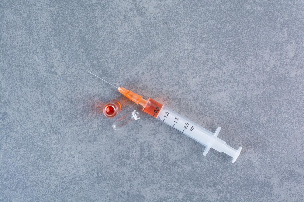 Syringe with red serum on marble surface