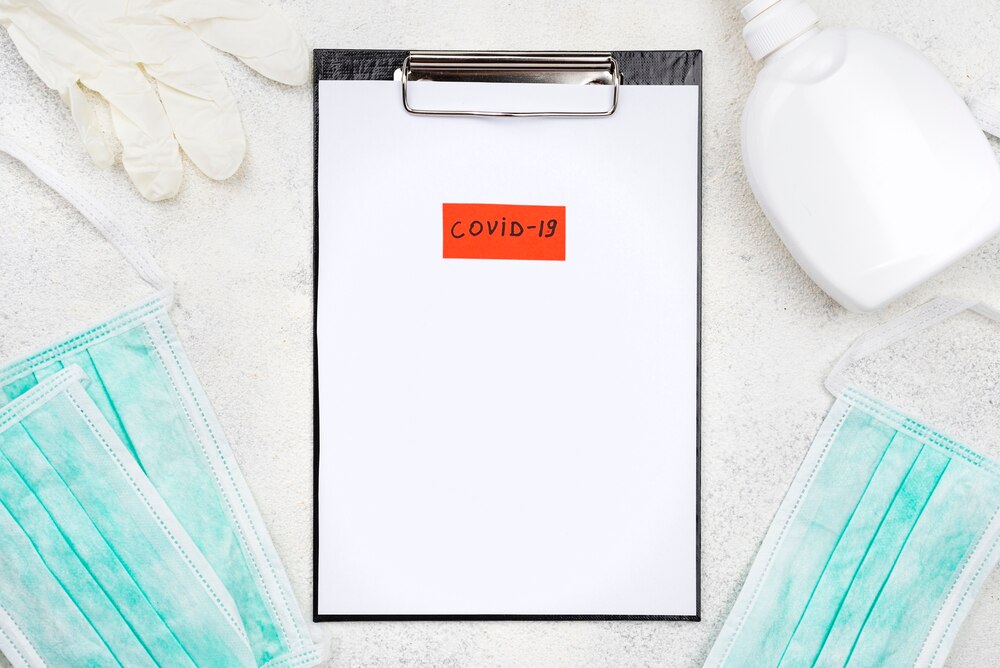 Medical desk composition with covid-19 tag on clipboard